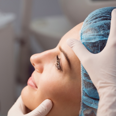 Armonización Orofacial 7 Hands of doctor examining womans face for cosmetic treatment at clinic