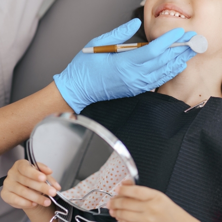 Ortodoncia Convencional 10 Cute little girl sitting on a modern dental chair and having dental consultation with dentist