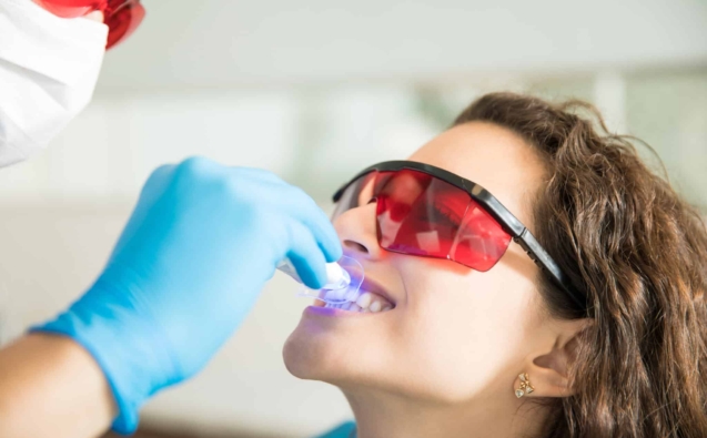 Closeup of young woman having her teeth whitened with ultraviolet light in a dental clinic